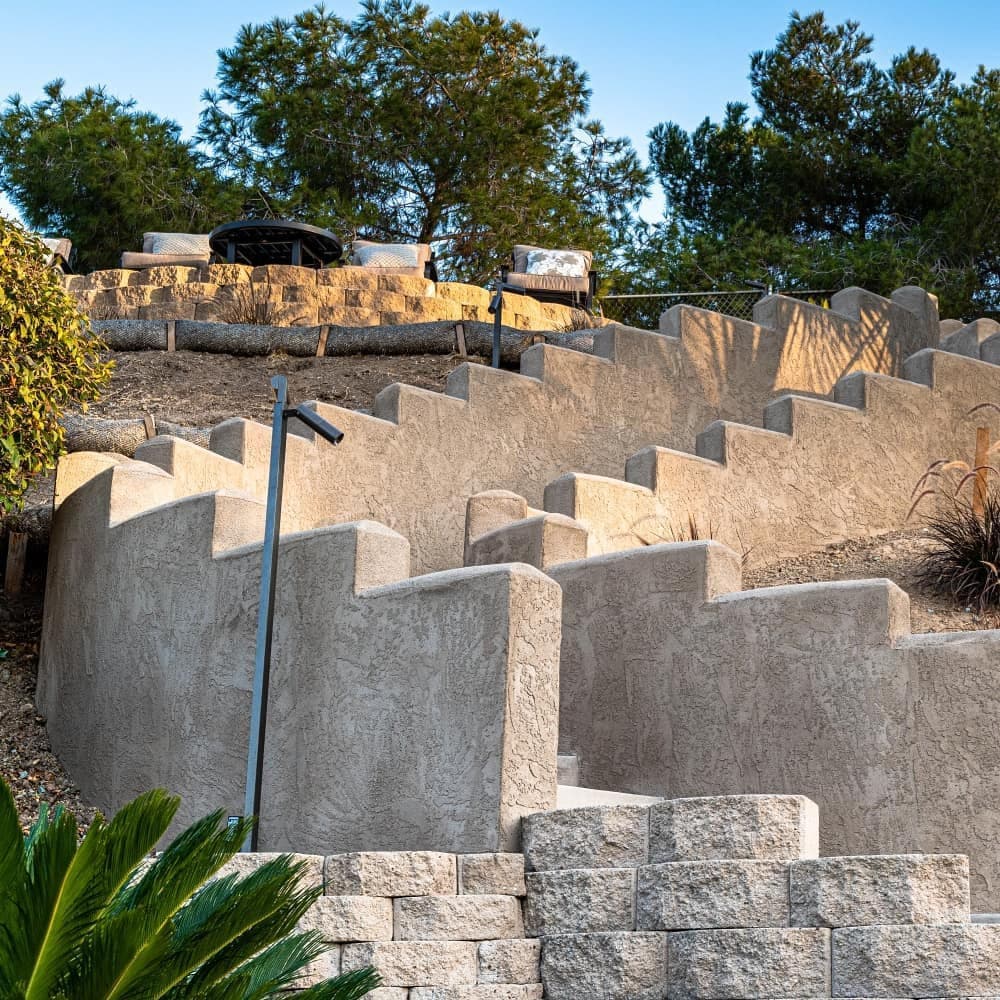 Terraced landscaping with stone walls and steps surrounded by greenery and trees.