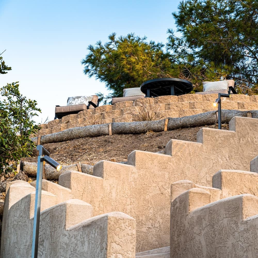 Staircase leading to a scenic terrace with outdoor seating and trees in the background.