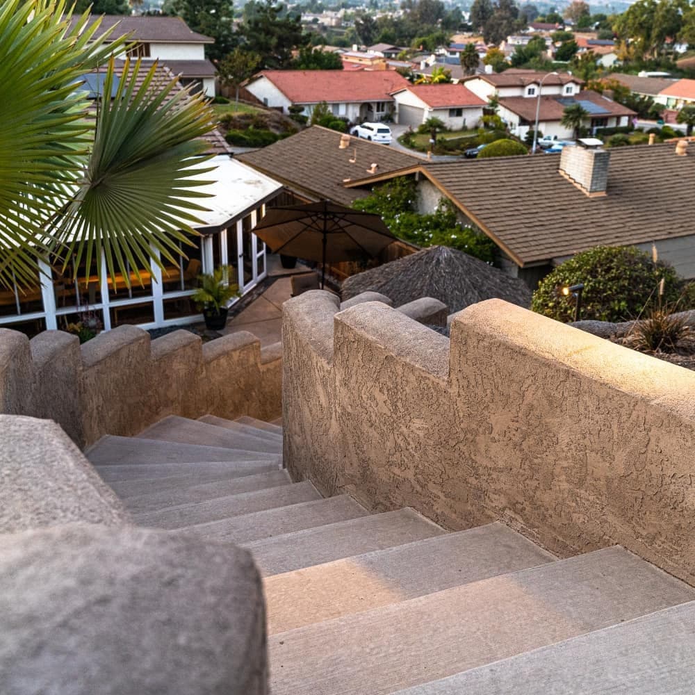 Stone staircase leading down to suburban homes with lush greenery and scenic views.