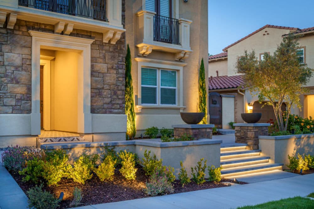 Elegant home exterior with stone accents, landscaped garden, and soft outdoor lighting.