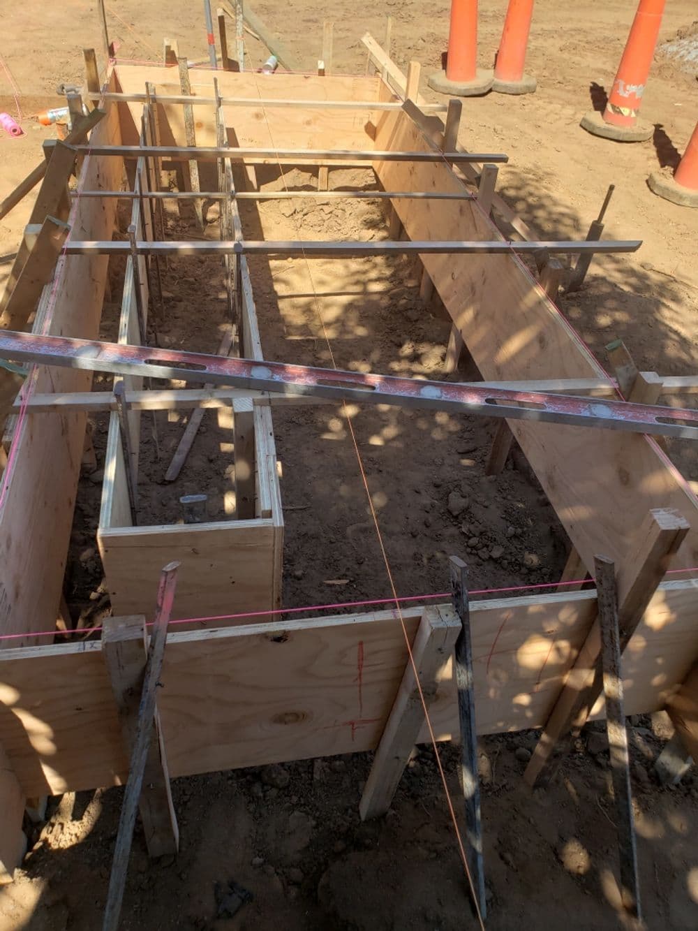 Construction site with wooden forms for concrete foundation and rebar setup.