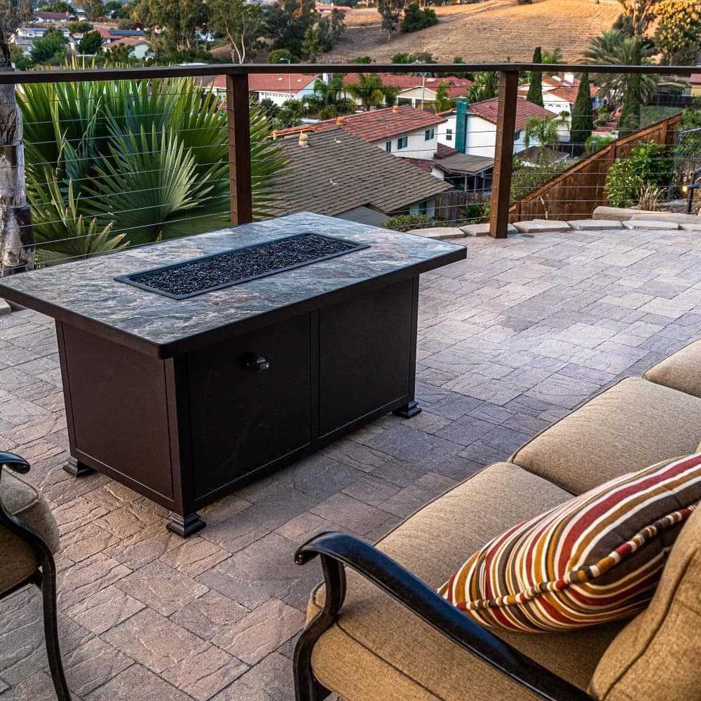 Fire pit table on patio overlooking homes and landscape in a serene outdoor setting.