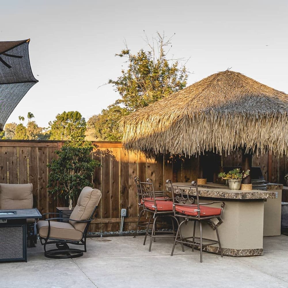 Tropical outdoor patio with seated bar, thatched roof, and comfortable lounge area.