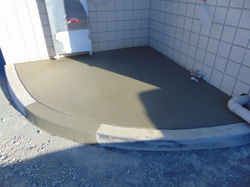 Freshly poured concrete slab in a construction area, showcasing smooth finish and curved edges.