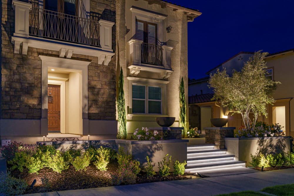Elegant house entrance at night with landscaped garden and soft outdoor lighting.