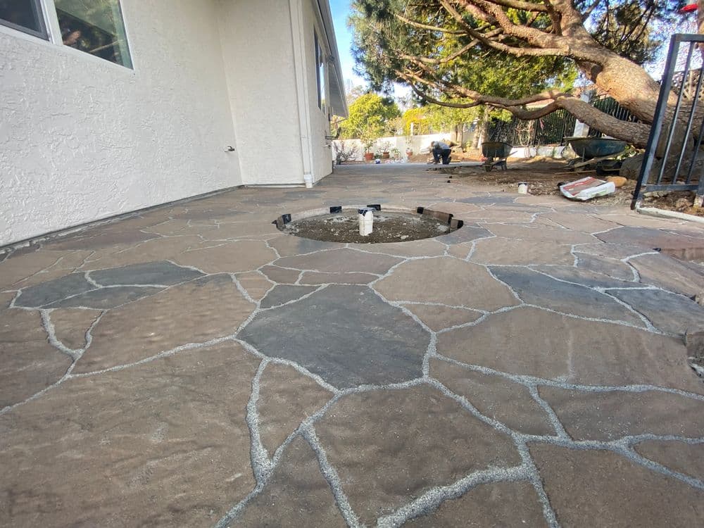 Patterned stone patio with a central fountain in a residential outdoor space.