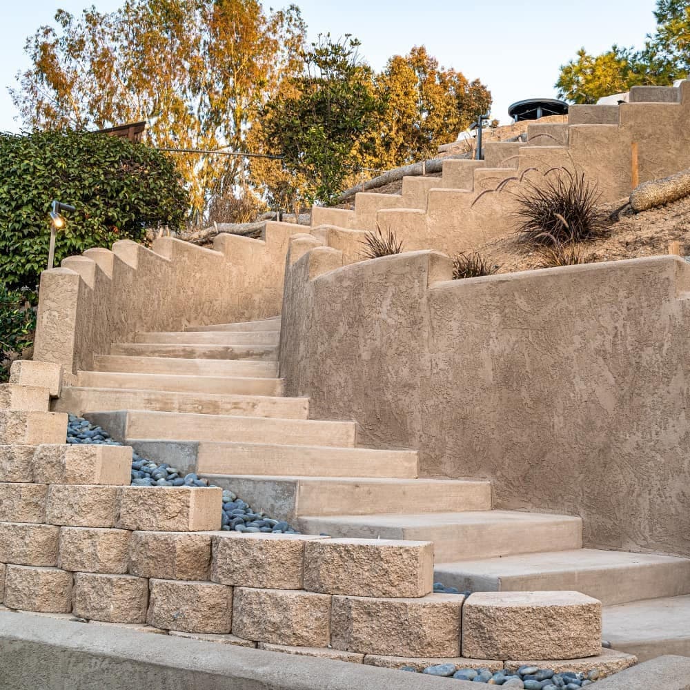 Modern outdoor staircase with textured walls and landscaped surroundings.