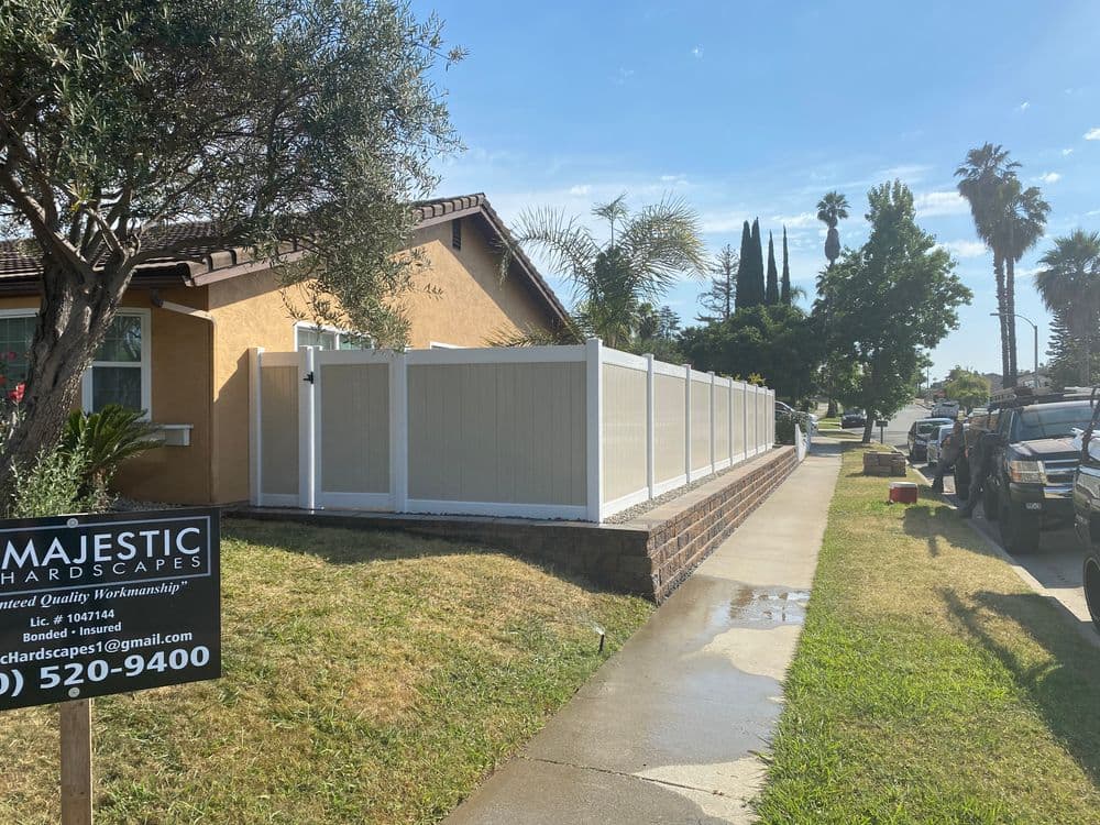 Residential property with a new vinyl fence, palm trees, and clear blue sky. Contact Majestic Hardscapes.