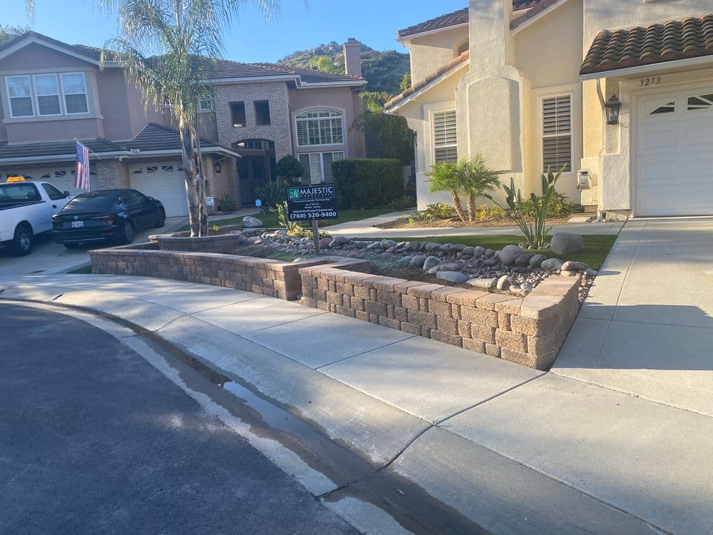 Home exterior with landscaped rock garden and for sale sign in a residential neighborhood.