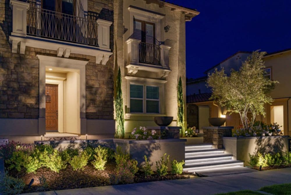 Elegant modern home exterior at night with landscape lighting and stone accents.