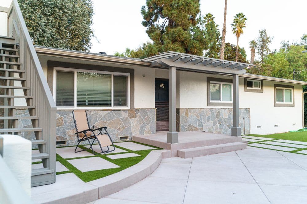 Modern home exterior with stone accents, landscaped yard, and stylish pergola.