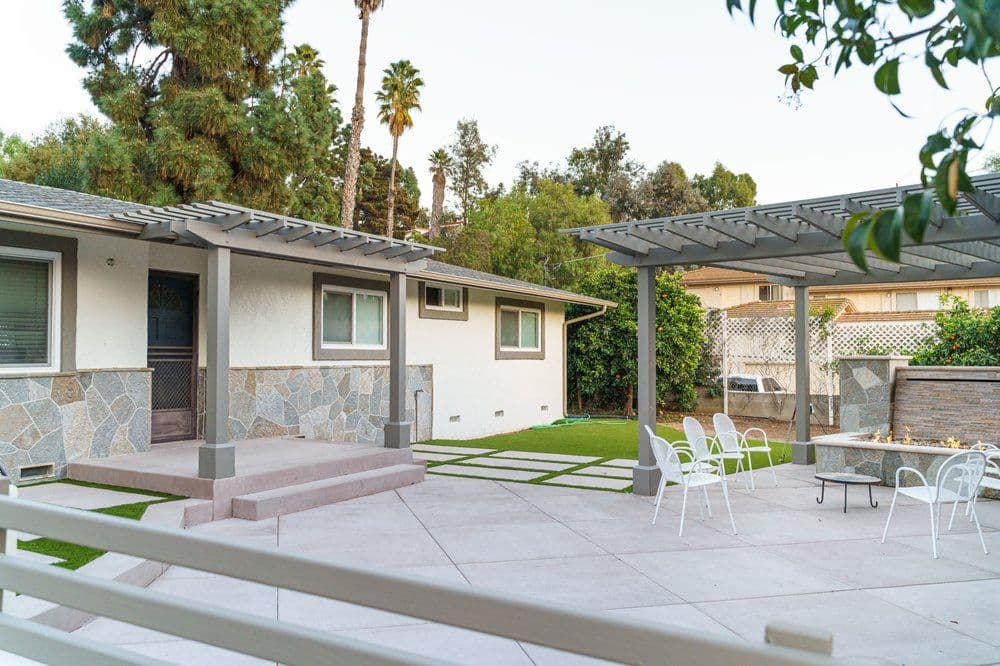 Modern backyard with patio, pergola, and stone features in a residential setting.