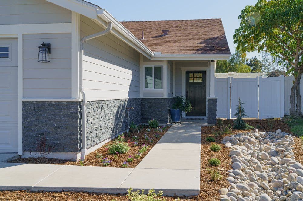 Charming home exterior with stone accents, landscaped pathway, and flowering plants.